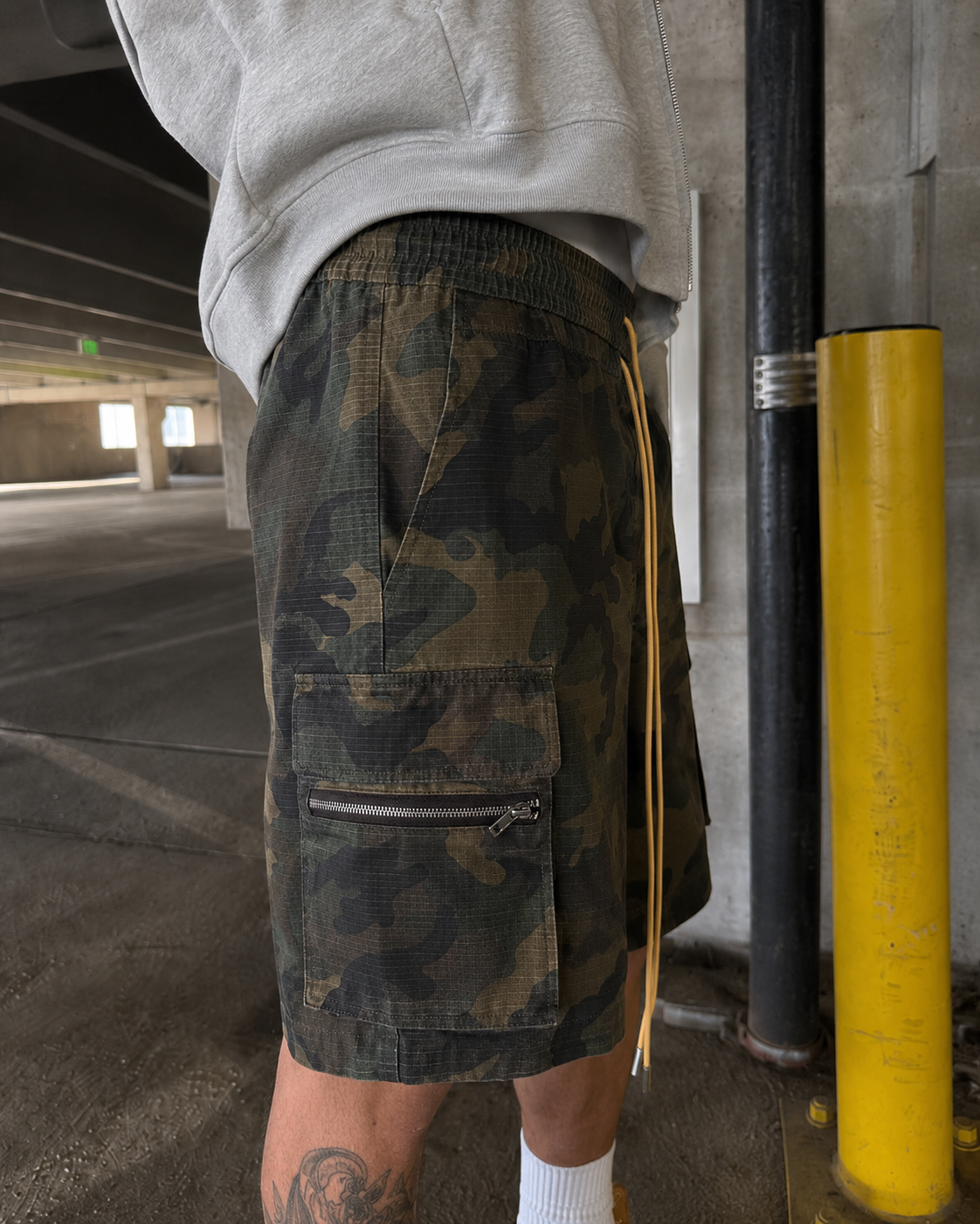 Camo Shorts worn from the side with cargo pocket and yellow drawstring detail