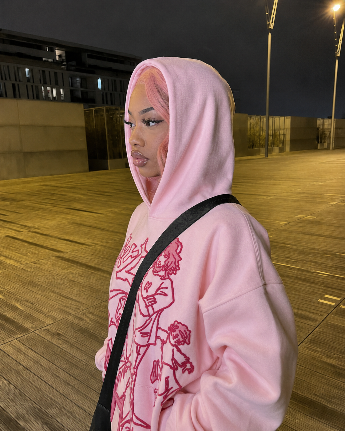 Pink cartoon hoodie worn side view with hood detail