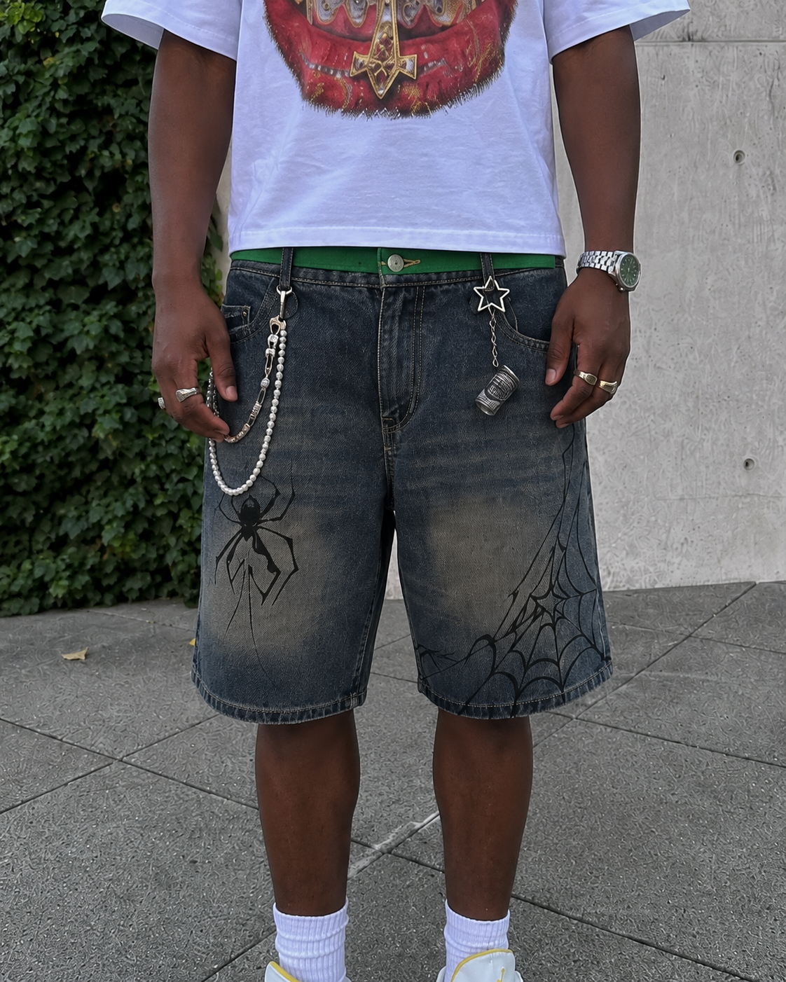 Detail of the Spider Shorts with spider and web graphics on washed denim
