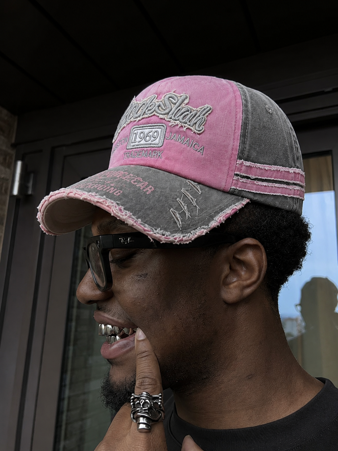 Casquette vintage rose et grise portée streetwear en gros plan