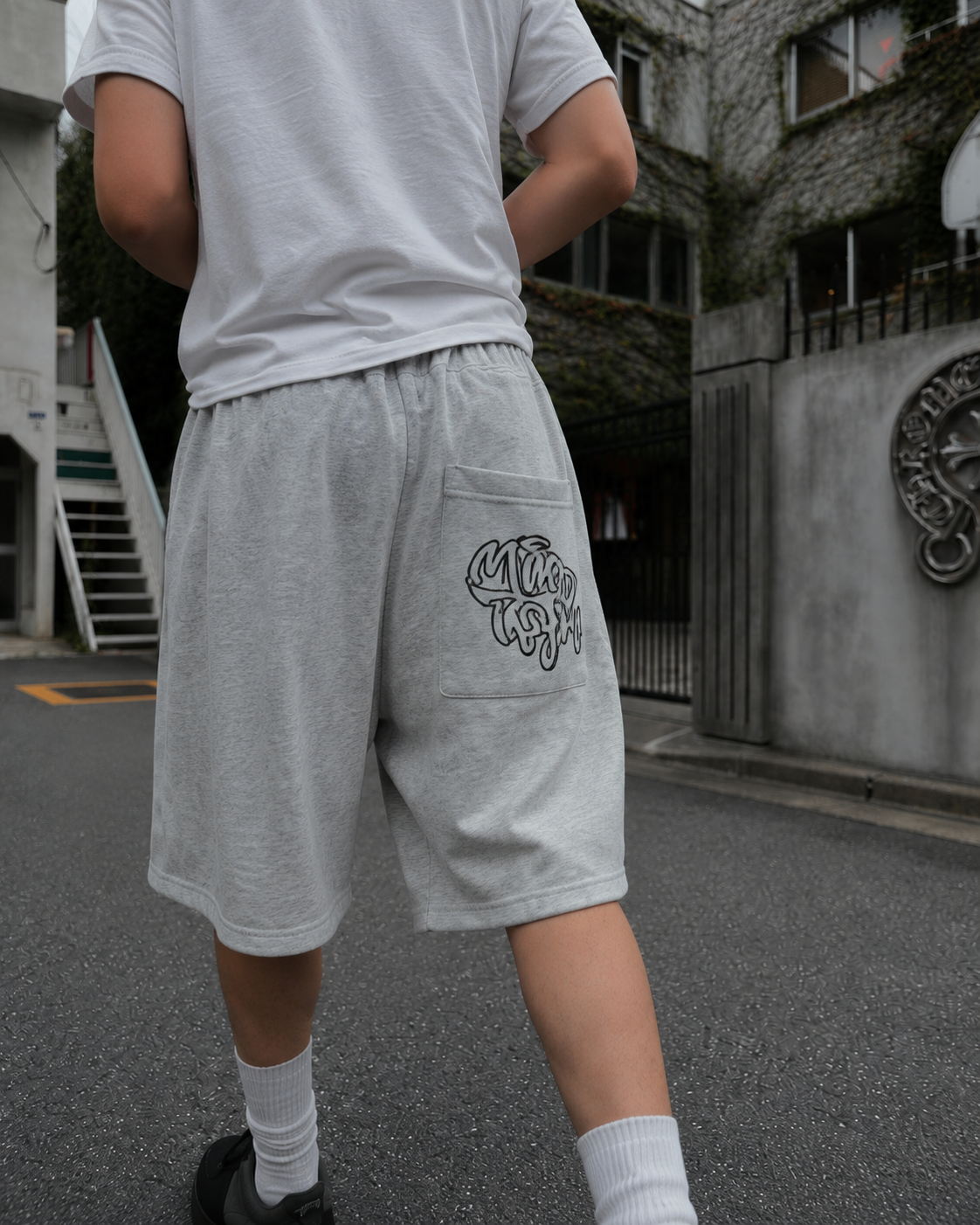 Grey graffiti shorts worn from the back in a streetwear outfit in Tokyo
