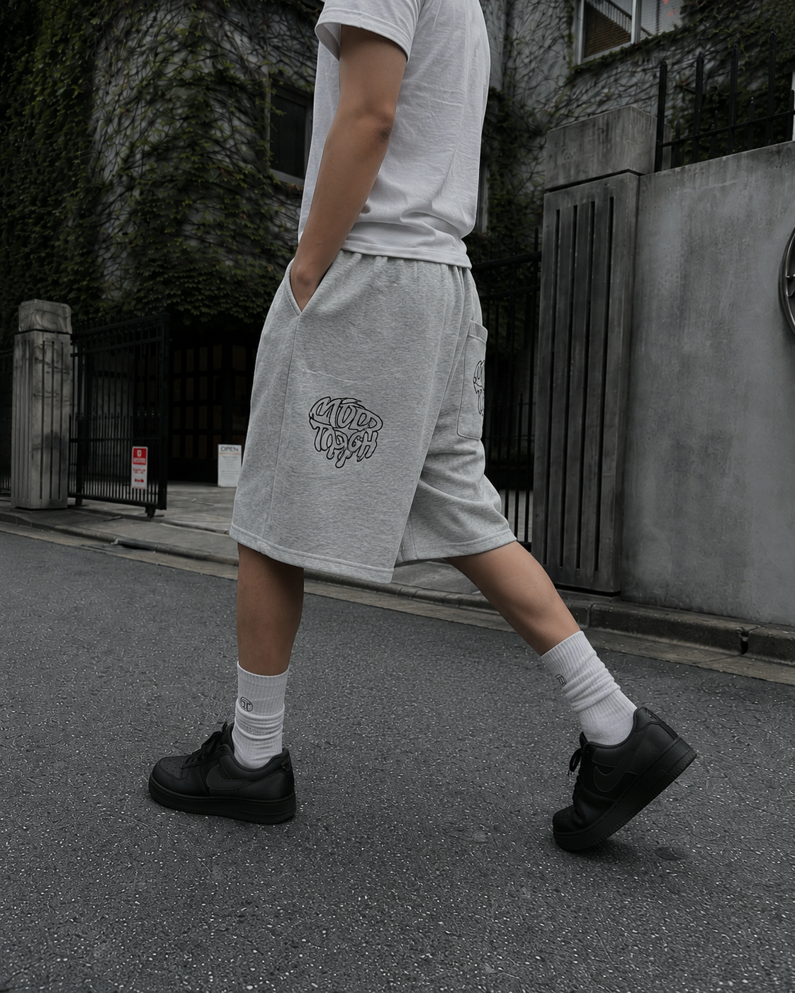 Grey graffiti shorts worn side view while walking on a Tokyo street