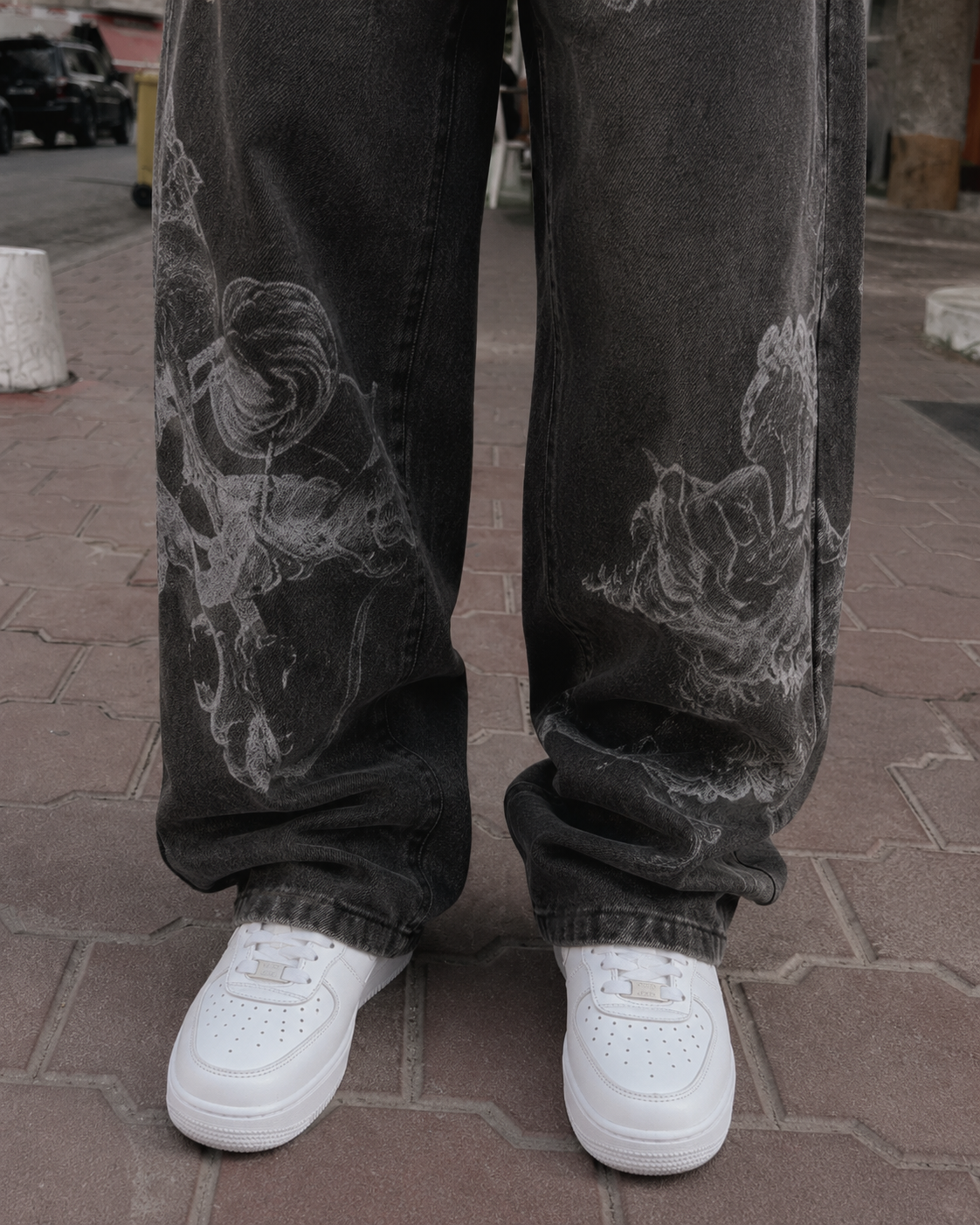 Close-up of Jean Ange black baggy jeans with angel print near the hem