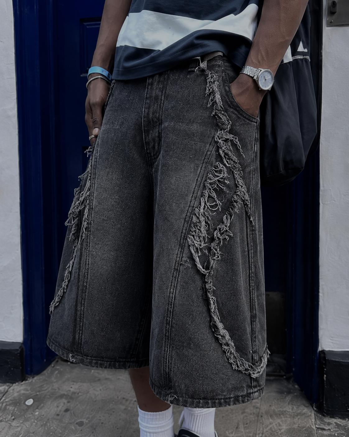 Close-up of diagonal frayed denim strips on black jorts