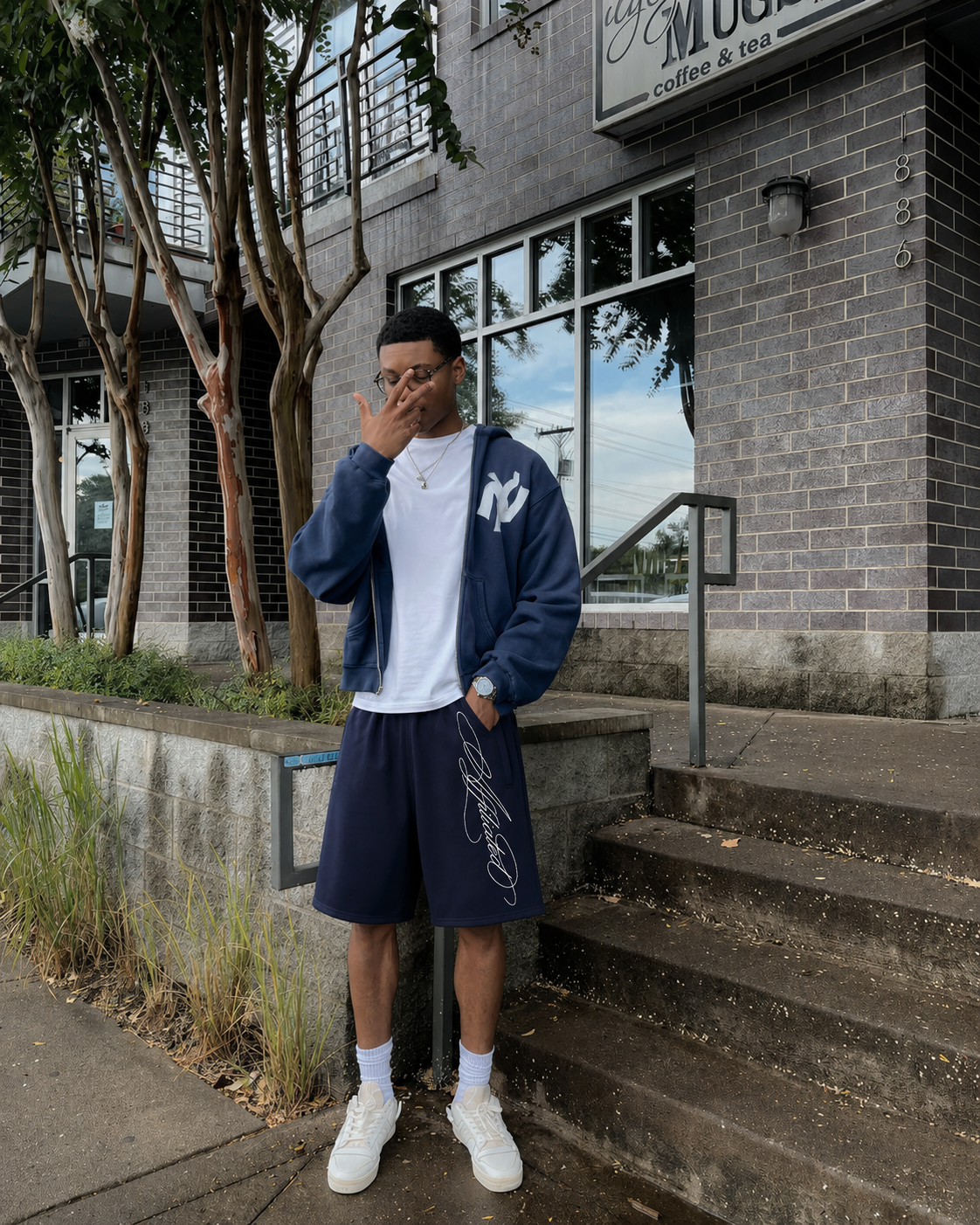 Short baggy bleu marine avec signature blanche porté dans un outfit streetwear