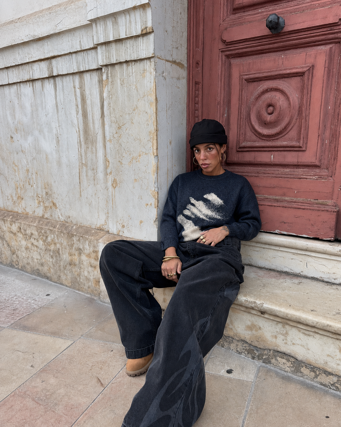 Face graphic sweater worn seated with baggy jeans