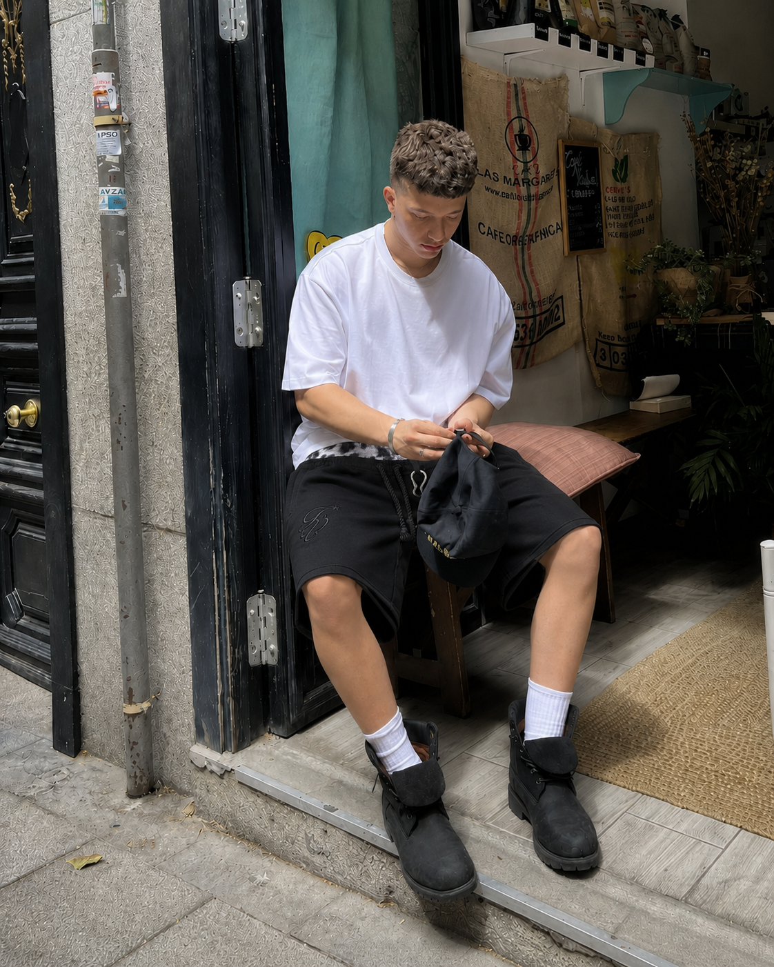 Short double ceinture noir camo porté en tenue urbaine devant un café